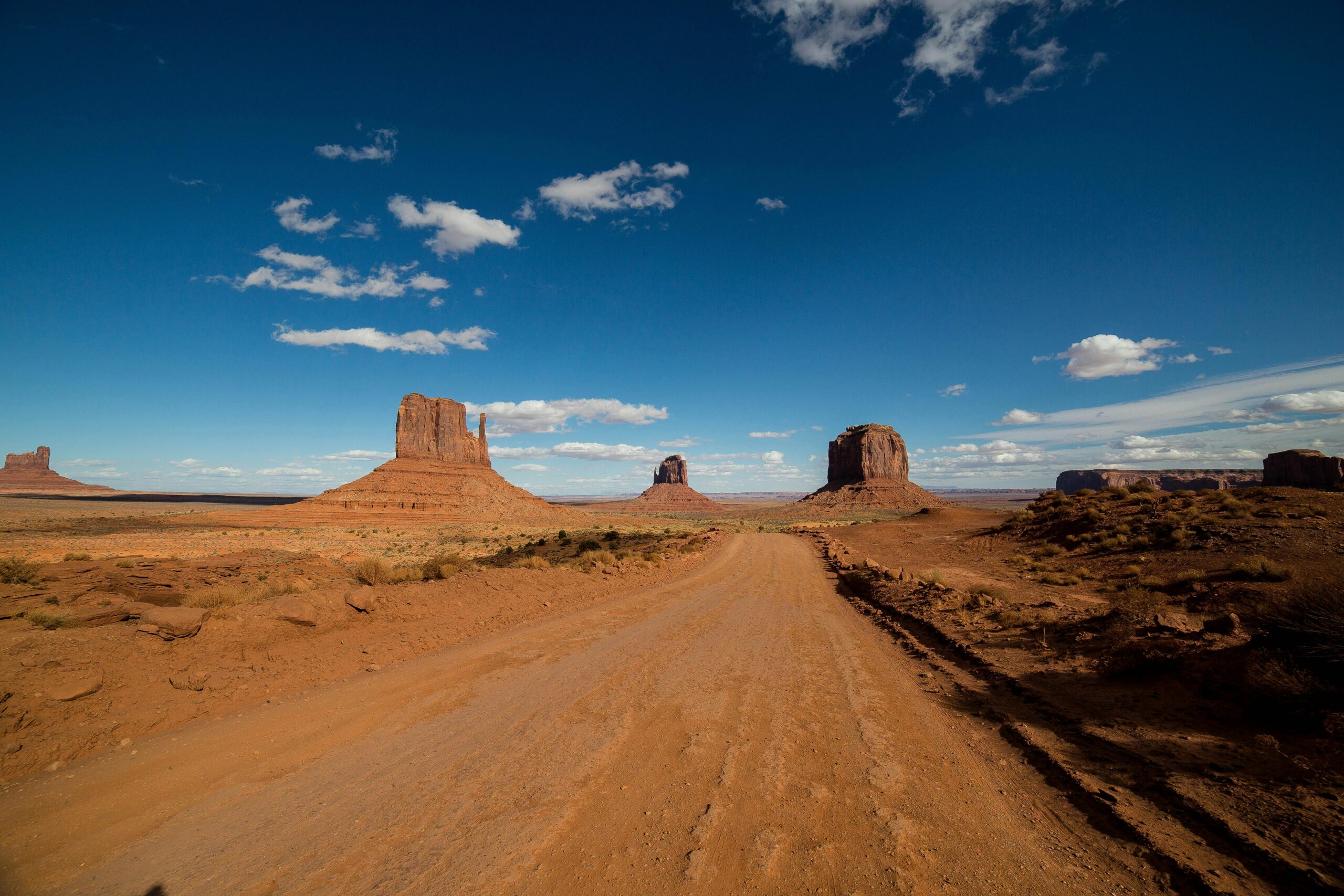 Explore the desolate beauty of Monument Valley's buttes under a vibrant sky.