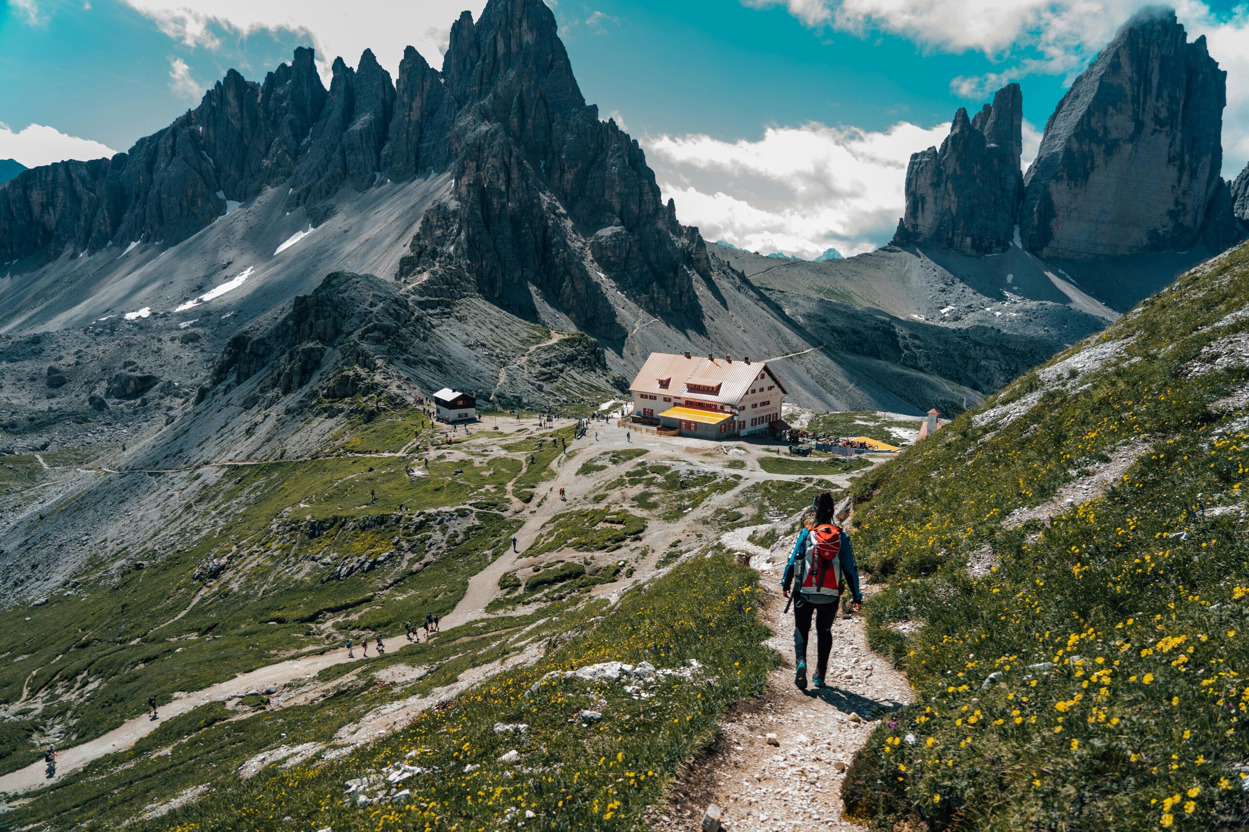 Woman hiking on a scenic trail in the Dolomites with stunning mountain views.