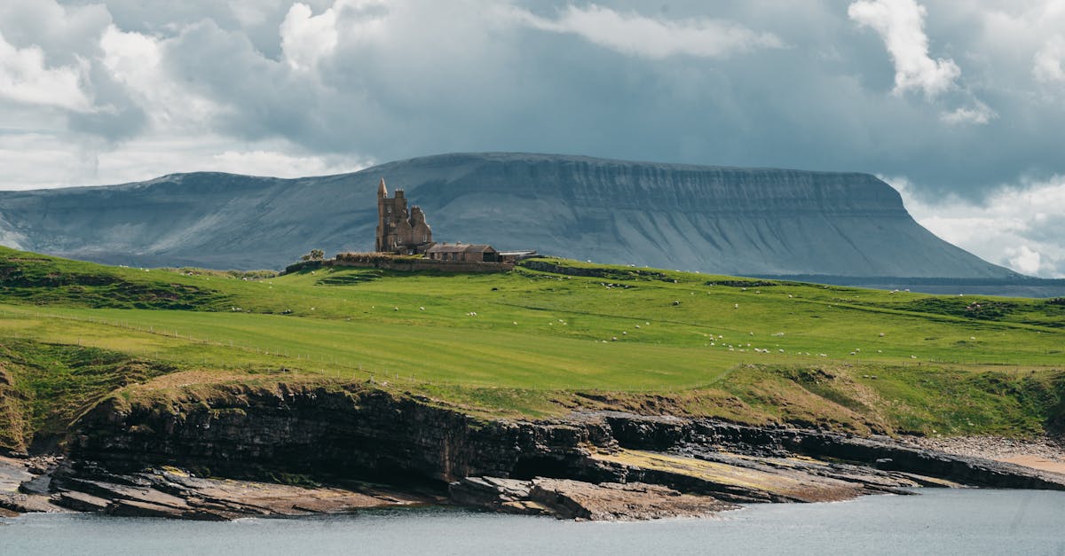 Scenic view of Classiebawn Castle with dramatic cliffs and lush greenery in County Sligo, Ireland.