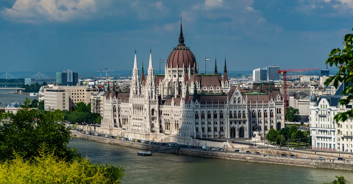 Scenic view of Budapest's iconic Parliament Building beside the Danube River, showcasing Gothic Revival architecture.